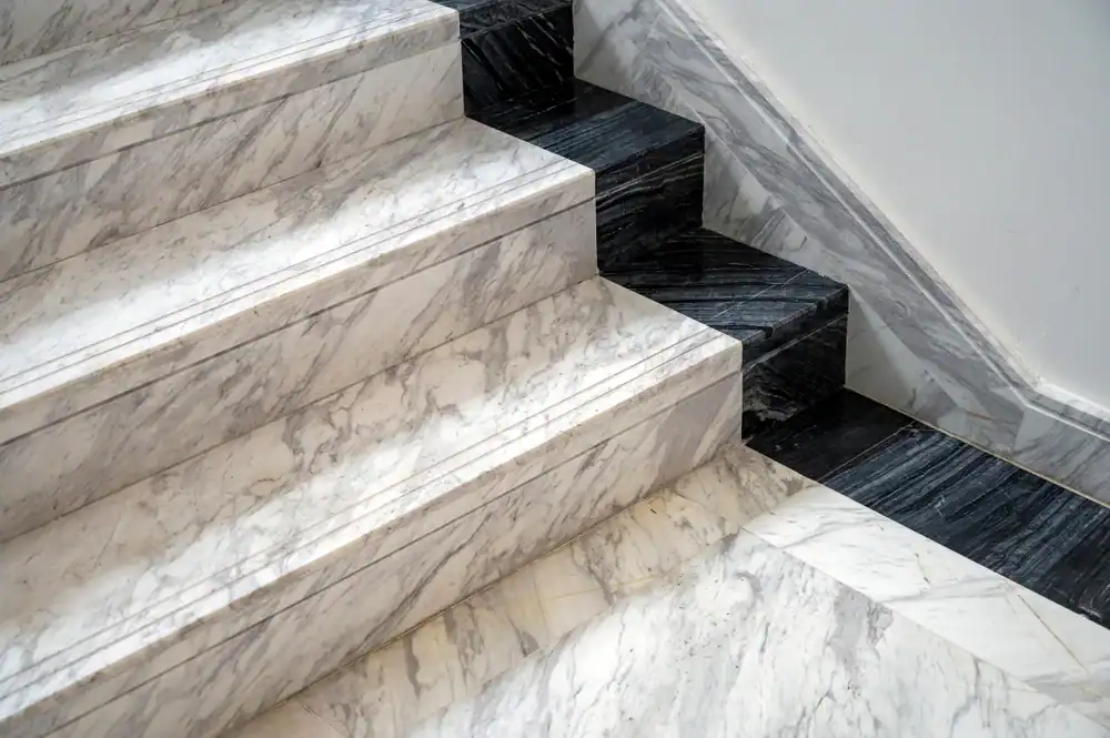 Marble staircase with alternating white and dark gray steps and matching marble flooring, showcasing a modern and elegant interior design—perfectly maintained with expert marble restoration in Nassau & Suffolk County, NY.
